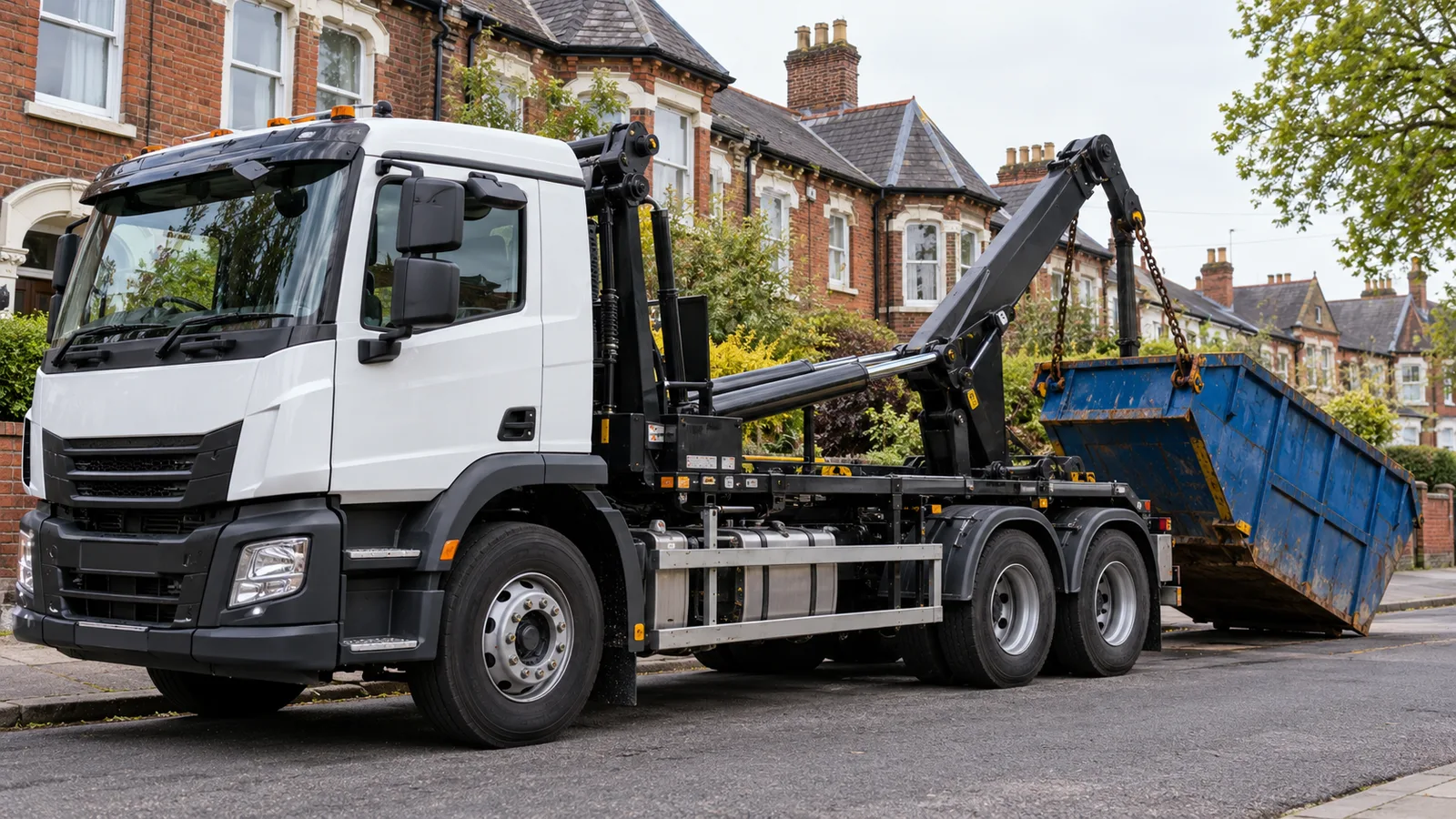 UK skip-loading lorry with visible cab and lifting arms beside a residential renovation
